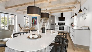 A modern kitchen with a central island, stainless steel appliances, and pendant lighting.