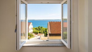 A view from an open window overlooking a coastal area with buildings and a sea. - Stunning apartment in Rtina with WiFi (Rtina)