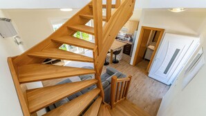 A wooden spiral staircase leading to a living area with a sofa and a kitchen in the background. - Stunning apartment in Rtina with WiFi (Rtina)