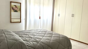 A bedroom with a bed, a wardrobe, a mirror, and a window with curtains. - SE090 - Marzocca, comfortable three-room apartment 150 meters from the sea (Marzocca)