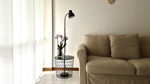 A living room with a sofa, a floor lamp, and a potted orchid plant. - SE090 - Marzocca, comfortable three-room apartment 150 meters from the sea (Marzocca)