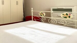 Een hotelkamer met een bed, een kledingkast, een nachtkastje en een klein bureau met een stoel.