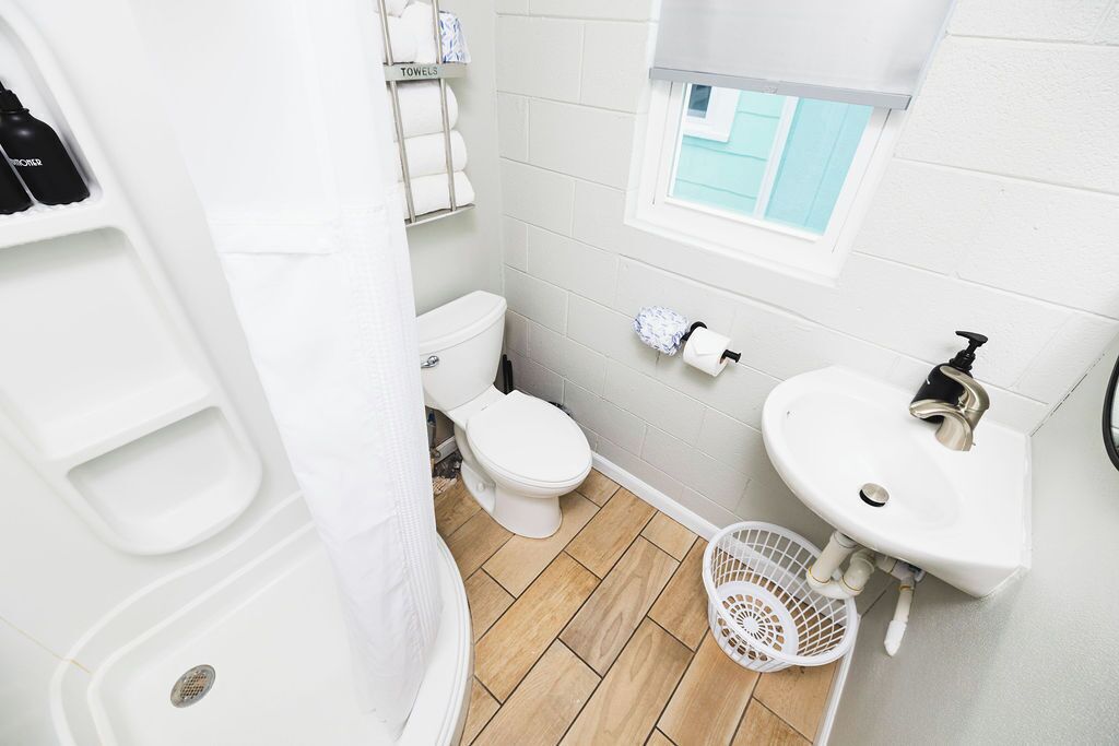 A bathroom with a toilet, sink, and shower.