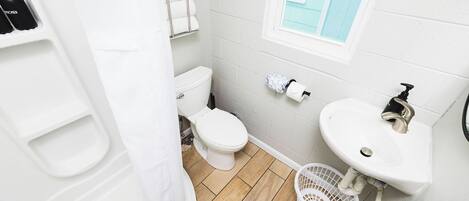A bathroom with a toilet, sink, and shower.