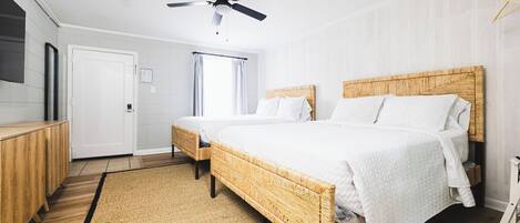 A modern bedroom with a large bed, a ceiling fan, a wooden headboard, and a small bedside table.
