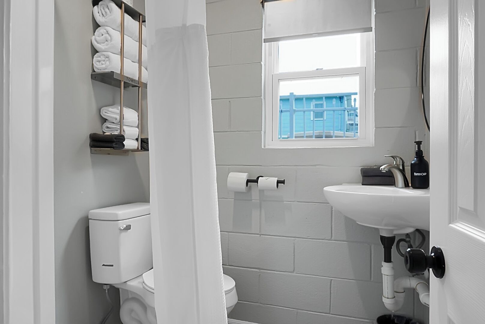 A bathroom with a toilet, a sink, a window, and a towel rack.
