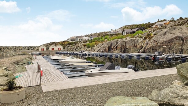 A marina with boats docked, a wooden dock, and houses on a rocky hillside. - 4 bedroom cozy home in Sveio (Sveio)