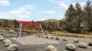 A swing set in a natural setting with a gravel ground and scattered rocks. - 4 bedroom cozy home in Sveio (Sveio)
