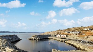 A coastal scene with a stone pier leading into calm waters, surrounded by rocky terrain and a few buildings. - 4 bedroom cozy home in Sveio (Sveio)