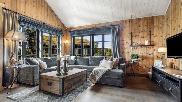 Een ruime woonkamer met een groot raam, een houten plafond en een gezellige open haard.