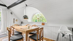 A dining area with a wooden table and chairs, a window with a view of greenery, a white ceiling, and a white radiator. - Beautiful home in Hemmet with WiFi (Hemmet)