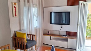 A living room with a sofa, chairs, a coffee table, a TV, and a sliding door leading to a balcony. - 2 Bedroom Villa in Saly (Saly)