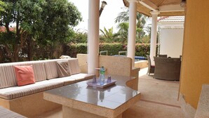 A sunlit outdoor seating area with a stone table, striped cushions, and a water bottle. - 2 Bedroom Villa in Saly (Saly)