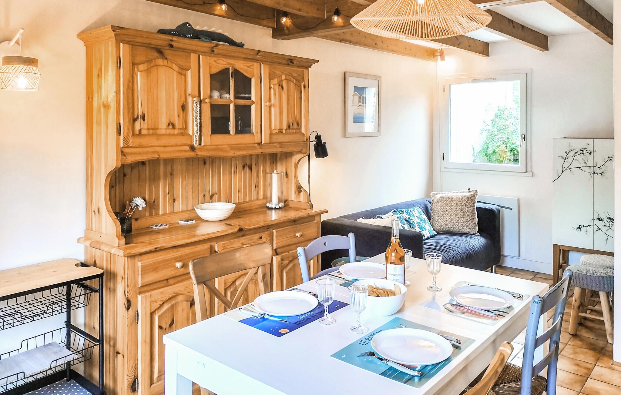 A dining area with a wooden cabinet, a dining table set for four, and a sofa in the background.