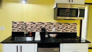 Cocina compacta con microondas, lavavajillas y salpicadero de azulejos.