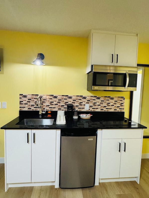 Cocina compacta con microondas, lavavajillas y salpicadero de azulejos.