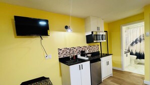 Una cocina compacta con televisión de pantalla plana, microondas y lavavajillas.