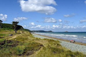 A coastal landscape with a grassy path leading to a beach, a few people walking, and a distant island. - Le Pommet - Erquy - Gîte (ERQUY)