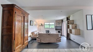 Un salon spacieux avec une grande armoire en bois, un canapé beige, une table basse et un téléviseur.