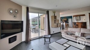 Un salon moderne avec un téléviseur à écran plat, un canapé et une table basse.