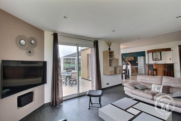A modern living room with a flat-screen TV, a sofa, and a coffee table. - Le Pommet - Erquy - Gîte (ERQUY)