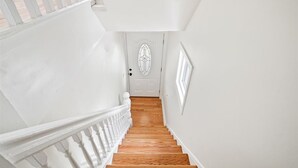 Una escalera con barandillas blancas que conduce a una puerta con un panel de vidrio decorativo.