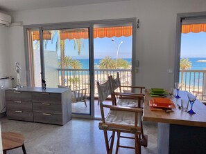 A room with a balcony, a desk, a chair, and a view of the beach. - Sea view next to historic center - Amirauté (Menton)