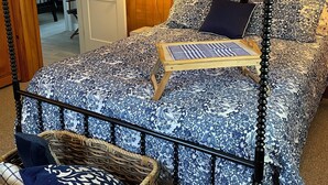 Una cama con dosel con un edredón de diseño azul y blanco, un cabecero de madera y una mesita de noche con una lámpara.