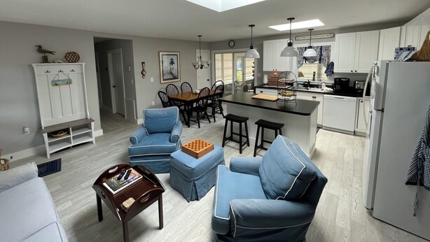 Una cocina moderna con una isla central, comedor con sillas y sala de estar con sofás.