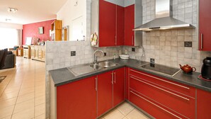 Una cocina moderna con gabinetes rojos, un lavamanos de acero inoxidable y una encimera negra.