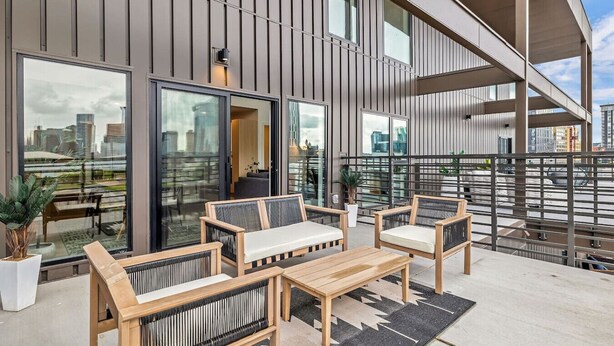 A modern outdoor seating area with a sofa and chairs, a small table, and a potted plant. - Beverly Nash, Incredible Skyline Views! Pool & Gym, Walk to Broadway (Nashville)
