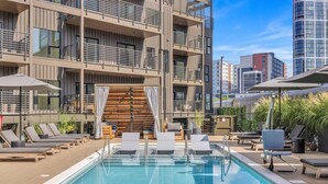 A rooftop pool area with lounge chairs, a wooden deck, and a view of surrounding buildings. - Beverly Nash, Incredible Skyline Views! Pool & Gym, Walk to Broadway (Nashville)