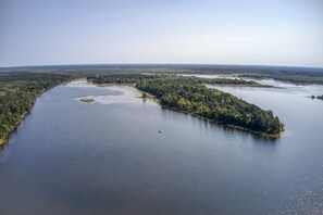 Luftaufnahme eines Flusses mit einer bewaldeten Insel und blauem Himmel.