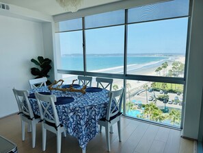 A dining area with a table set for four, overlooking a beach and ocean view. - Condo with stunning views of Pacific Ocean, Coronado Beaches & San Diego Bay! (Coronado)