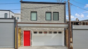 A two-story building with a garage door, a red door, and a stone facade. - @StayatNoMA (Washington)