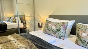 A modern hotel room with a large bed, a mirror, and two bedside lamps.
