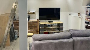 Ein Loft-Zimmer mit Fernseher, Holzmöbeln und einer Wendeltreppe.