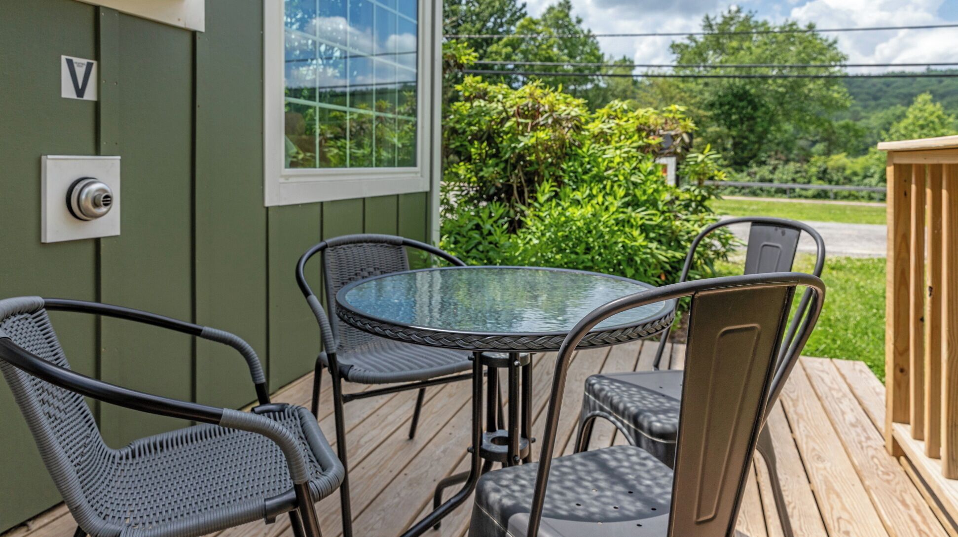 A covered outdoor seating area with a round glass table and four chairs.