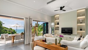 A modern living room with a wooden coffee table, white sofas, and a TV mounted on the wall. - Villa Divano by Sublime Samui Villas (Koh Samui)