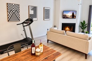 Una sala de estar con una cinta de correr, un sofá, una chimenea y obras de arte en la pared.