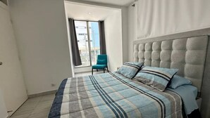 Ein Schlafzimmer mit einem großen Bett, einem Sessel und Blick ins Freie.