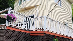 Ein zweistöckiges Haus mit Balkon, Satellitenschüssel und einem Garten mit Blumen.