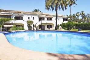 Una piscina con un edificio blanco al fondo.