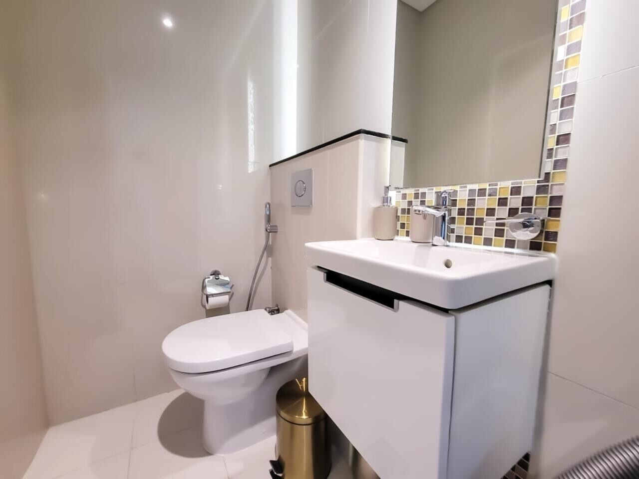 Un baño moderno con inodoro, lavamanos y espejo.