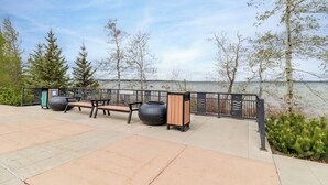 Un parc au bord de l’eau, équipé de bancs et d’une poubelle.