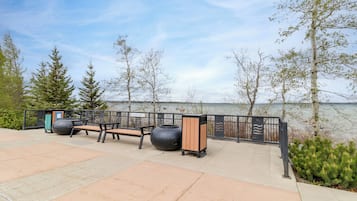 Un parc au bord de l’eau, équipé de bancs et d’une poubelle.