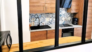 A compact kitchen with wooden cabinets, a tiled backsplash, and a coffee maker.