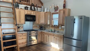 A kitchen with wooden cabinets, stainless steel appliances, a built-in oven, and a stainless steel refrigerator. - Tiny house hideaway just outside of town (Cody)
