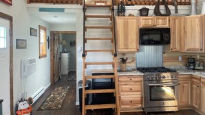 A kitchen with wooden cabinets, a stainless steel stove, and a wooden ladder. - Tiny house hideaway just outside of town (Cody)