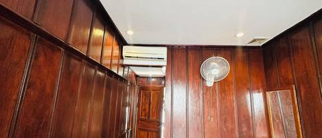 Un couloir étroit aux murs recouverts de lambris en bois, avec un appareil de climatisation fixé au mur.
